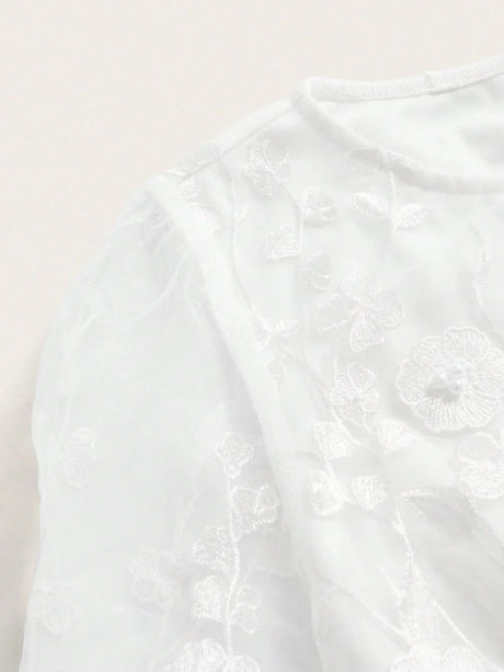This elegant white dress features delicate floral embroidery on sheer fabric, creating a soft and romantic look. The.