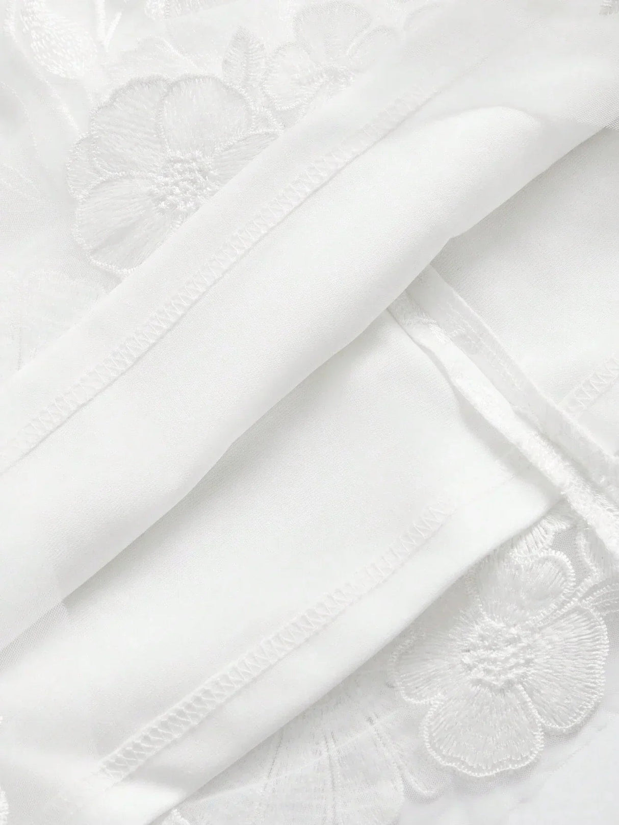 A delicate white dress featuring intricate floral embroidery, crafted from lightweight fabric that offers a soft and airy.