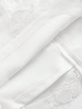 A delicate white dress featuring intricate floral embroidery, crafted from lightweight fabric that offers a soft and airy.