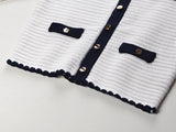 White knit cardigan with navy accents and gold buttons paired with a matching A-line skirt featuring a flared hem