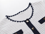 White knit cardigan with navy accents and gold buttons paired with a matching A-line skirt featuring a flared hem