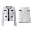 White knit cardigan with navy accents and gold buttons paired with a matching A-line skirt featuring a flared hem