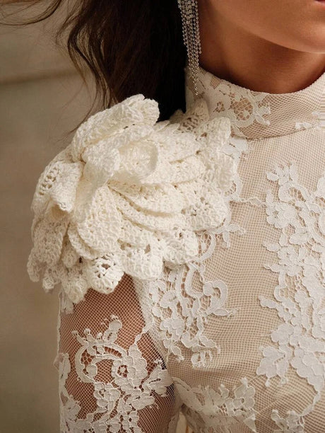 This exquisite white lace dress features intricate floral detailing on the shoulder, creating a romantic and feminine.
