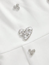 This elegant white dress features a flattering fit, adorned with sparkling crystal embellishments that add a touch of.