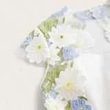 This elegant white dress features a delicate floral embroidery in soft blue and vibrant green, creating a fresh and romantic.