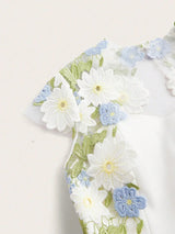 This enchanting white dress features delicate floral embroidery in soft blue and green hues, lending a fresh and romantic.
