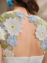 Delicate and charming, this dress features a stunning back adorned with intricate floral embroidery in soft shades of blue.