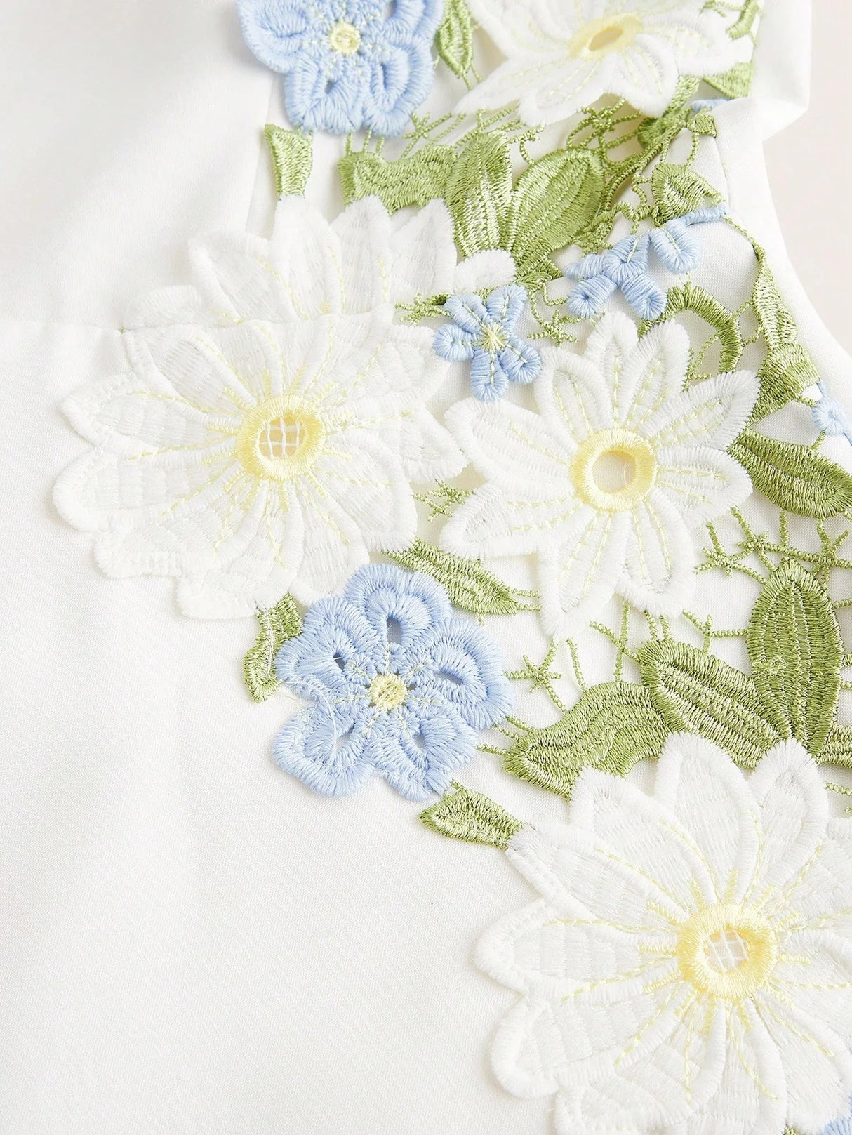 This charming white dress features delicate floral embroidery in soft shades of blue and green, creating a fresh and.