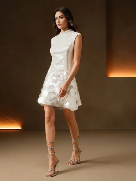 This elegant sleeveless white dress features a fitted bodice and a flared skirt adorned with shimmering sequins and delicate.