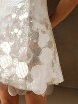 This enchanting white dress features a playful fit-and-flare silhouette adorned with shimmering sequins and large.