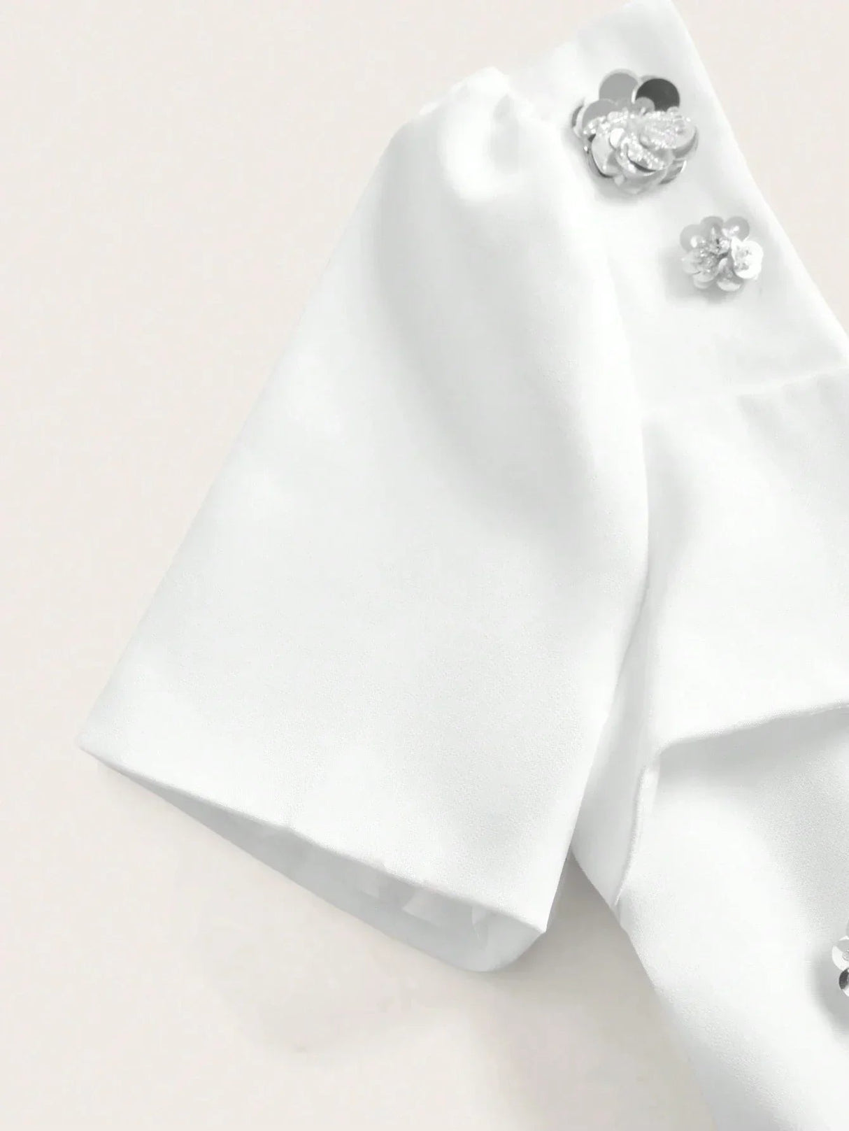 Elevate your wardrobe with this elegant white dress featuring short sleeves adorned with delicate floral embellishments..