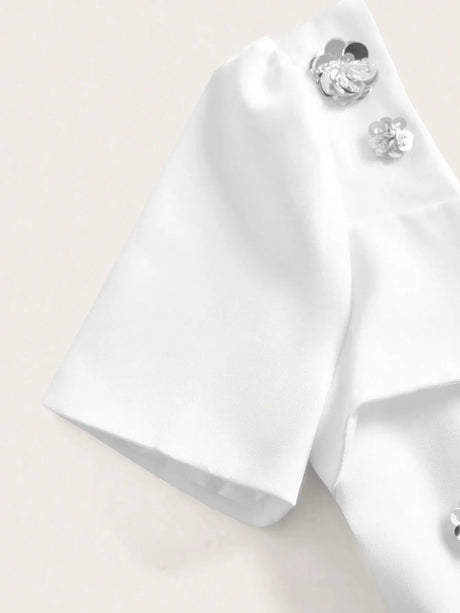 Elevate your wardrobe with this elegant white dress featuring short sleeves adorned with delicate floral embellishments..