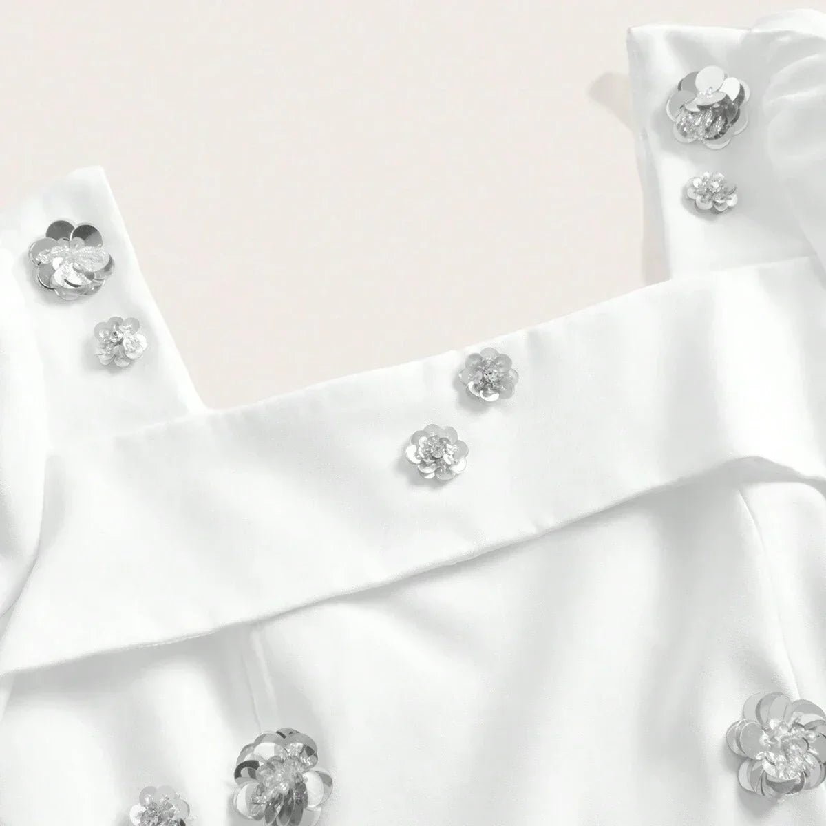 This elegant white dress features delicate silver flower embellishments that add a touch of glamour to its chic design. The.