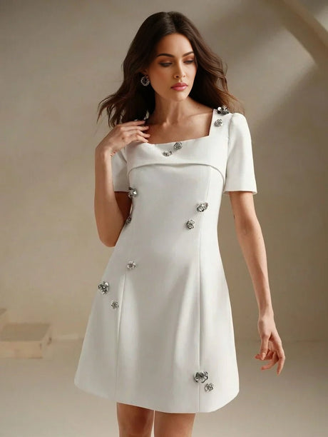This elegant white dress features a chic square neckline and short sleeves, gracefully accentuated by shimmering floral.