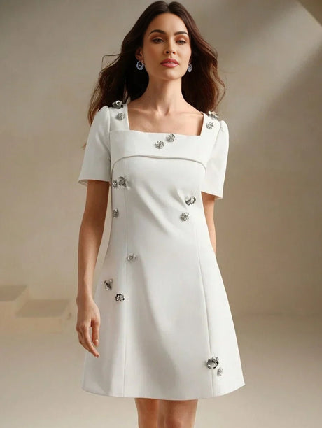 Elevate your wardrobe with this charming white mini dress, featuring a square neckline and short sleeves adorned with.