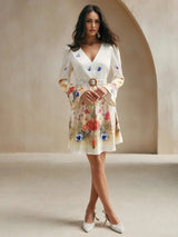 This enchanting floral dress features a soft cream base adorned with vibrant blooms in shades of pink, blue, and orange,.