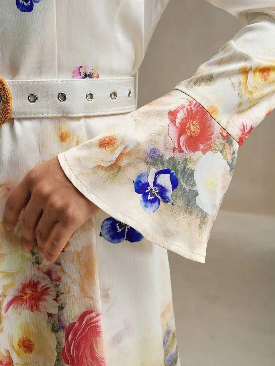 This elegant dress features a soft, flowy silhouette adorned with vibrant floral patterns in shades of pink, red, and blue,.
