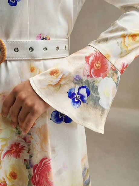 This elegant dress features a soft, flowy silhouette adorned with vibrant floral patterns in shades of pink, red, and blue,.
