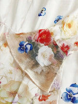 This stunning dress features a delicate floral pattern with vibrant hues of red, blue, and soft yellow blossoms against a.