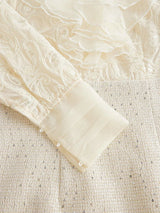 This elegant cream dress features intricate pastel embroidery and delicate flowing ruffles, creating a romantic and.