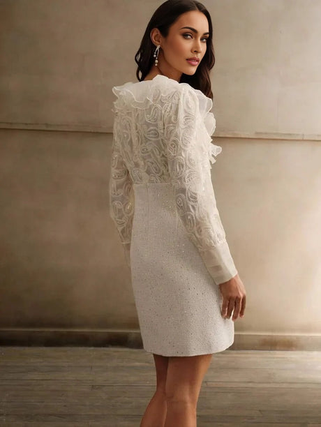 This stunning white dress features a fitted silhouette adorned with delicate ruffled detailing and floral textured sleeves,.