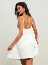 This elegant white mini dress features a playful fit-and-flare silhouette with delicate spaghetti straps and an alluring.