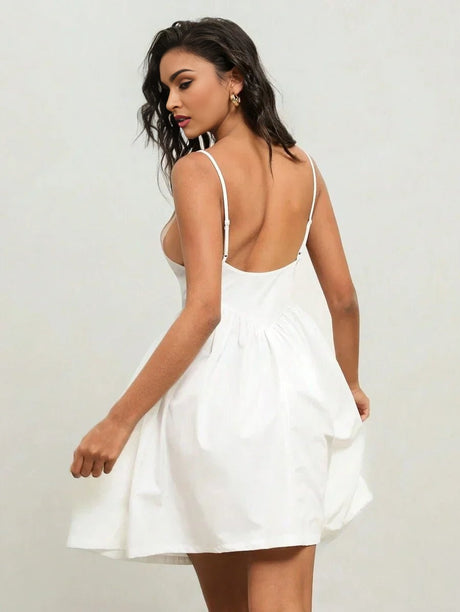 This elegant white mini dress features a playful fit-and-flare silhouette with delicate spaghetti straps and an alluring.