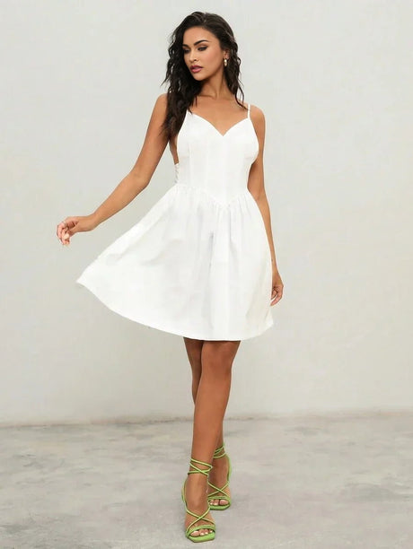 This charming white dress features a flattering A-line silhouette, complemented by delicate spaghetti straps and a deep.