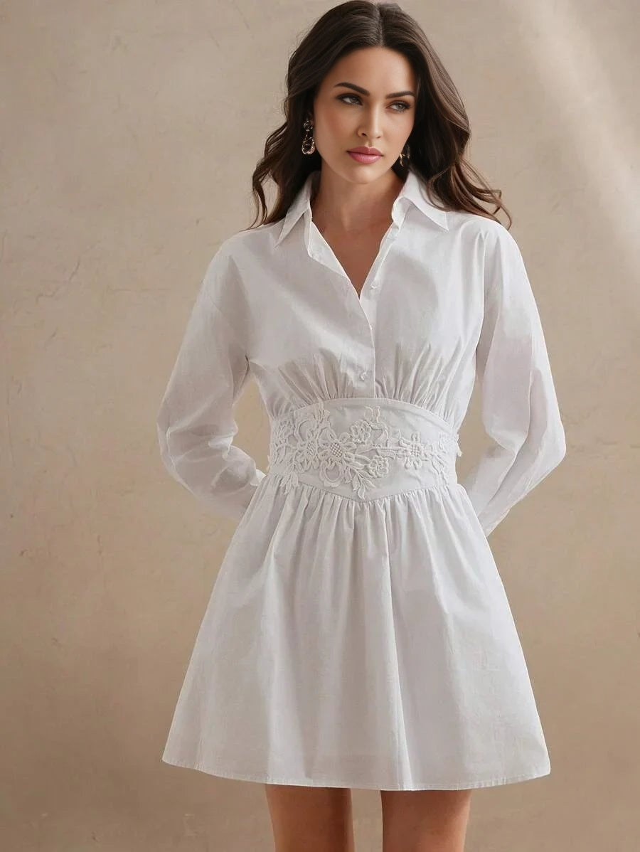 This stylish white shirt dress features a flattering fitted bodice with delicate floral embroidery at the waist and flowing.