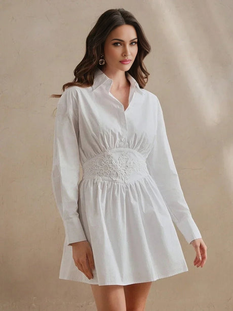 This elegant white shirt dress features a fitted bodice with intricate floral embroidery, creating a flattering silhouette.