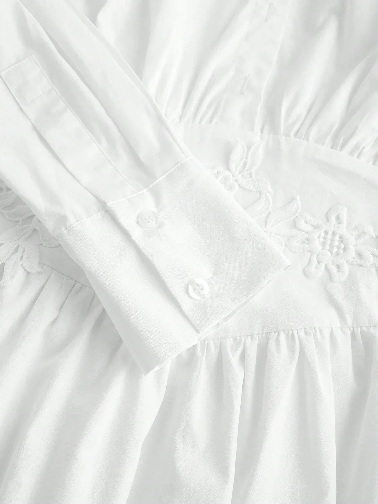 This elegant white dress features a delicate embroidered waistline, long sleeves with buttoned cuffs, and a soft, flowing.