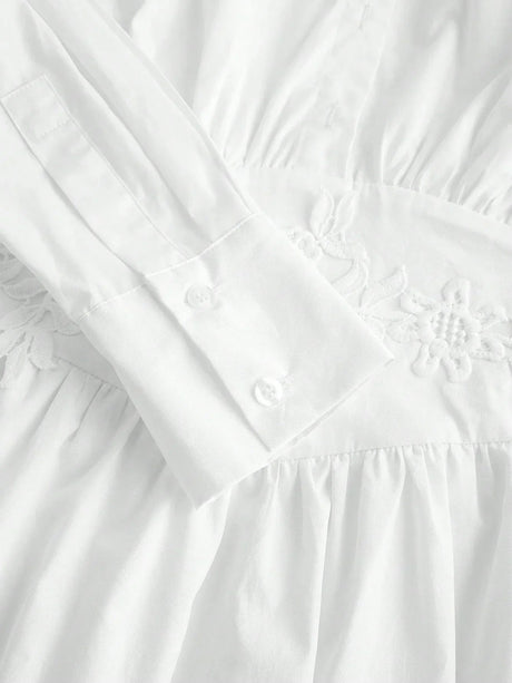 This elegant white dress features a delicate embroidered waistline, long sleeves with buttoned cuffs, and a soft, flowing.