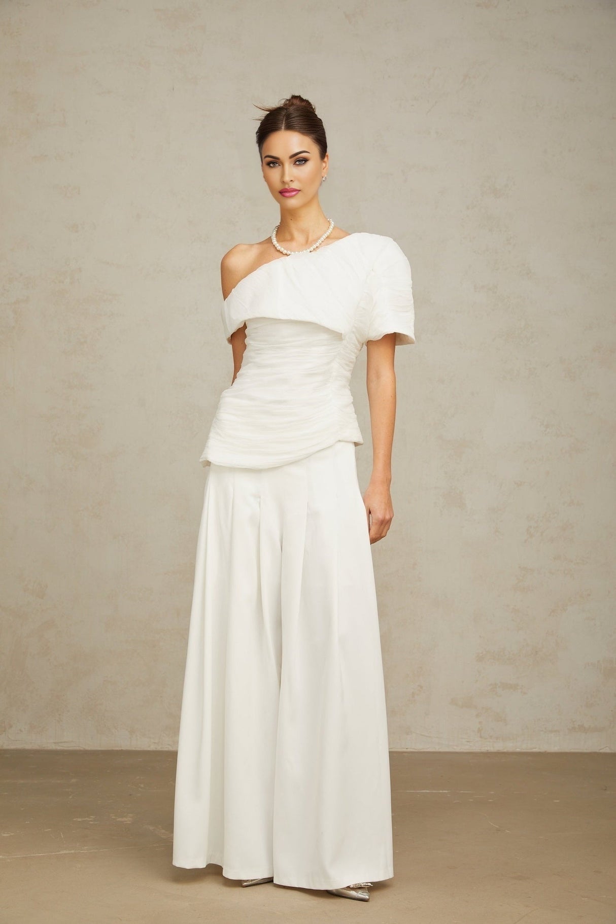 Matching white outfit set featuring a creased top and trousers worn by a model