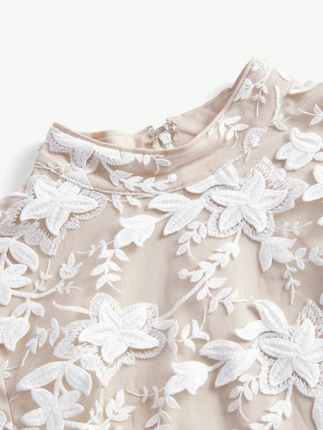Elegant beige dress adorned with intricate white floral embroidery, featuring a refined high neckline and a soft, flowing.