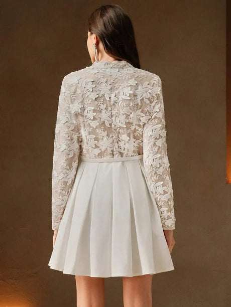 This elegant dress features a delicate sheer floral lace bodice in soft beige, beautifully complemented by a pleated white.