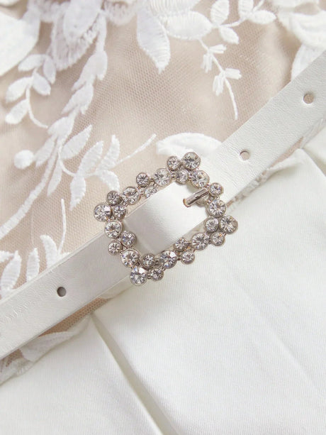 This elegant ivory dress features intricate floral embroidery on a delicate sheer overlay, complemented by a flattering.