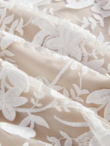 This elegant dress features a soft beige fabric adorned with intricate white floral embroidery, giving it a romantic and.