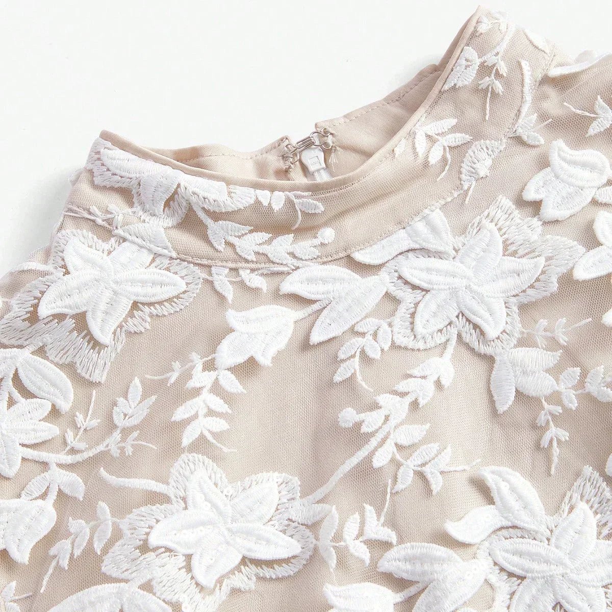 This elegant dress features a soft beige fabric adorned with intricate white floral embroidery, creating a stunning.