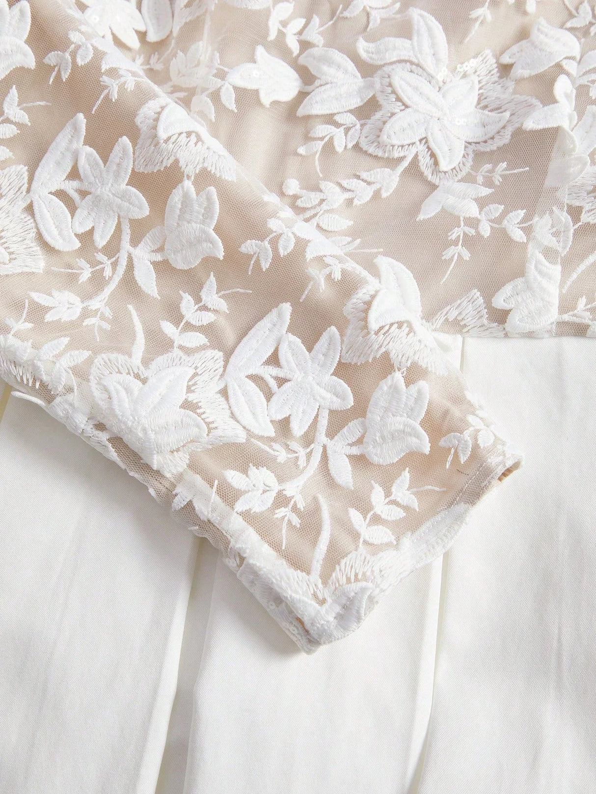 This elegant dress features a soft beige base adorned with delicate white floral embroidery, creating a romantic and.
