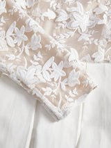 This elegant dress features a soft beige base adorned with delicate white floral embroidery, creating a romantic and.