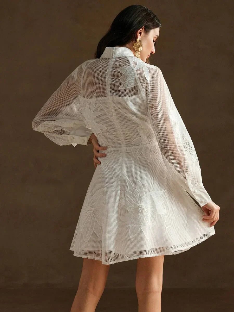 This enchanting white dress features a delicate sheer overlay with intricate floral embroidery, creating a lovely feminine.