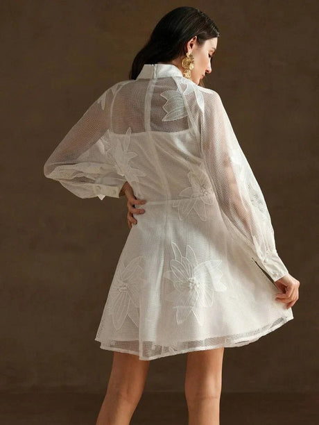 This enchanting white dress features a delicate sheer overlay with intricate floral embroidery, creating a lovely feminine.