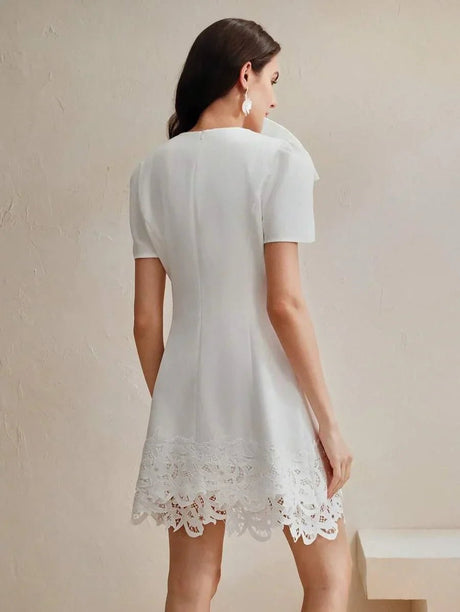 A charming white dress featuring a flared silhouette, short sleeves, and intricate lace detailing at the hem. The.