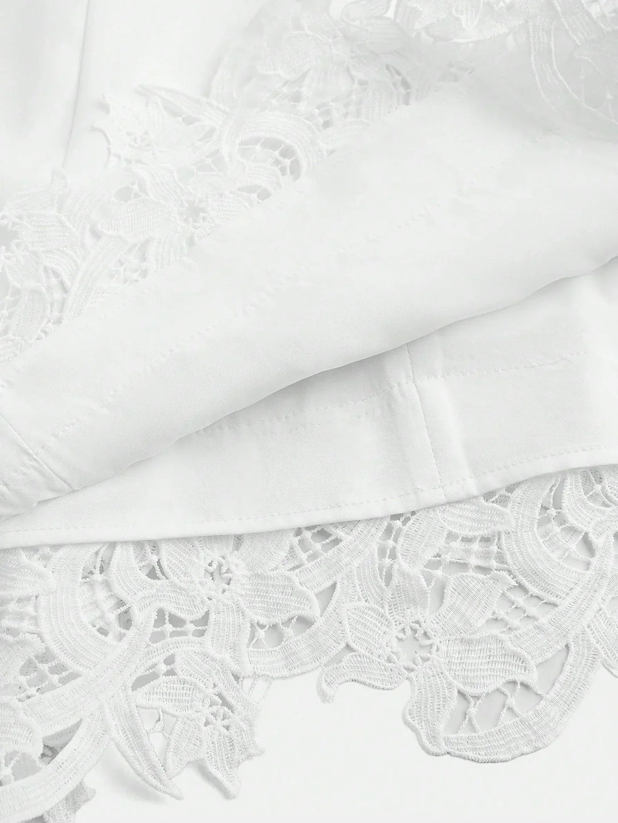 This elegant white dress features intricate floral lace detailing at the hem, adding a touch of sophistication to its.