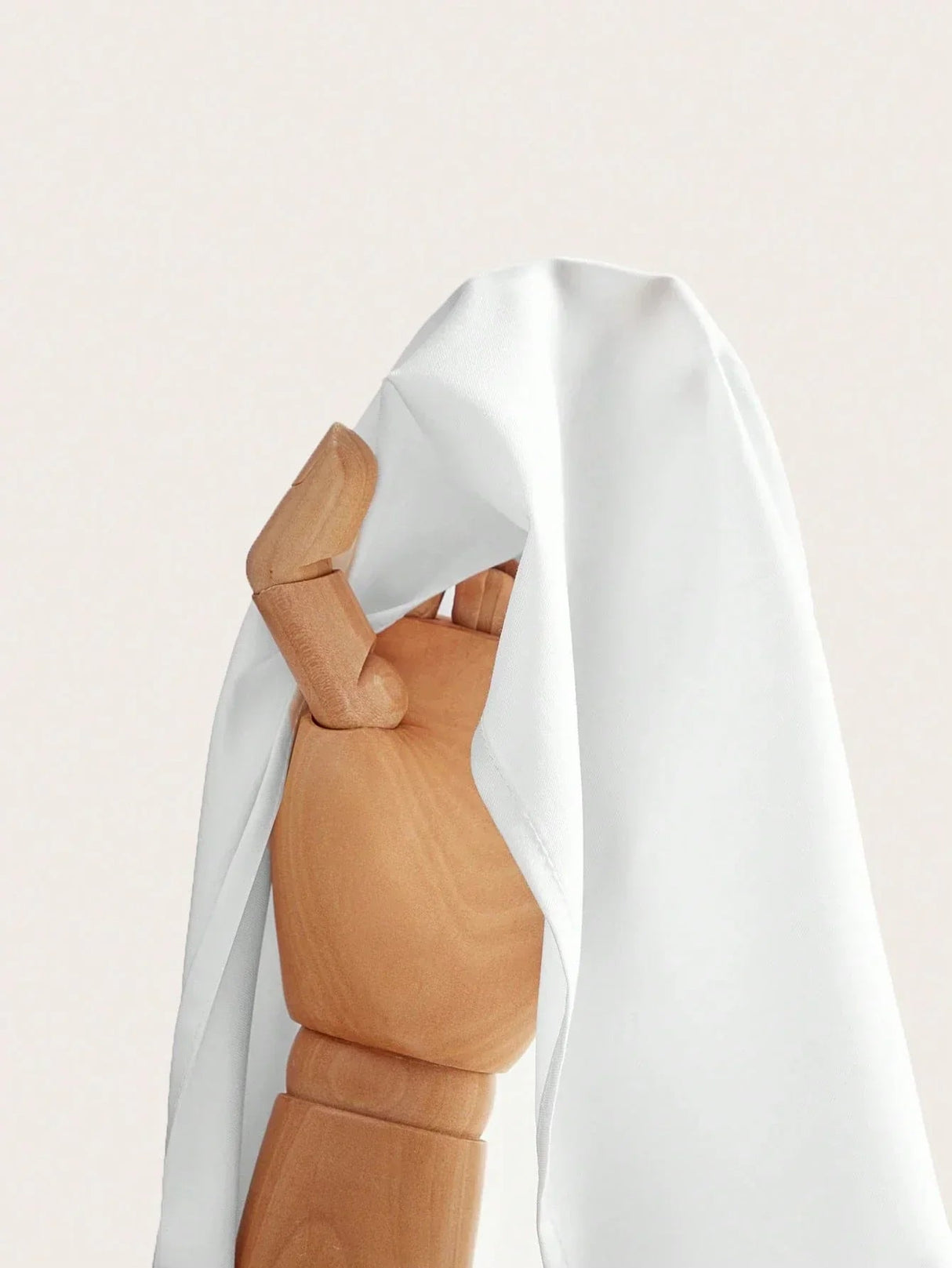 A flowing white dress drapes elegantly over a wooden mannequin, showcasing its soft fabric and relaxed fit. The lightweight.