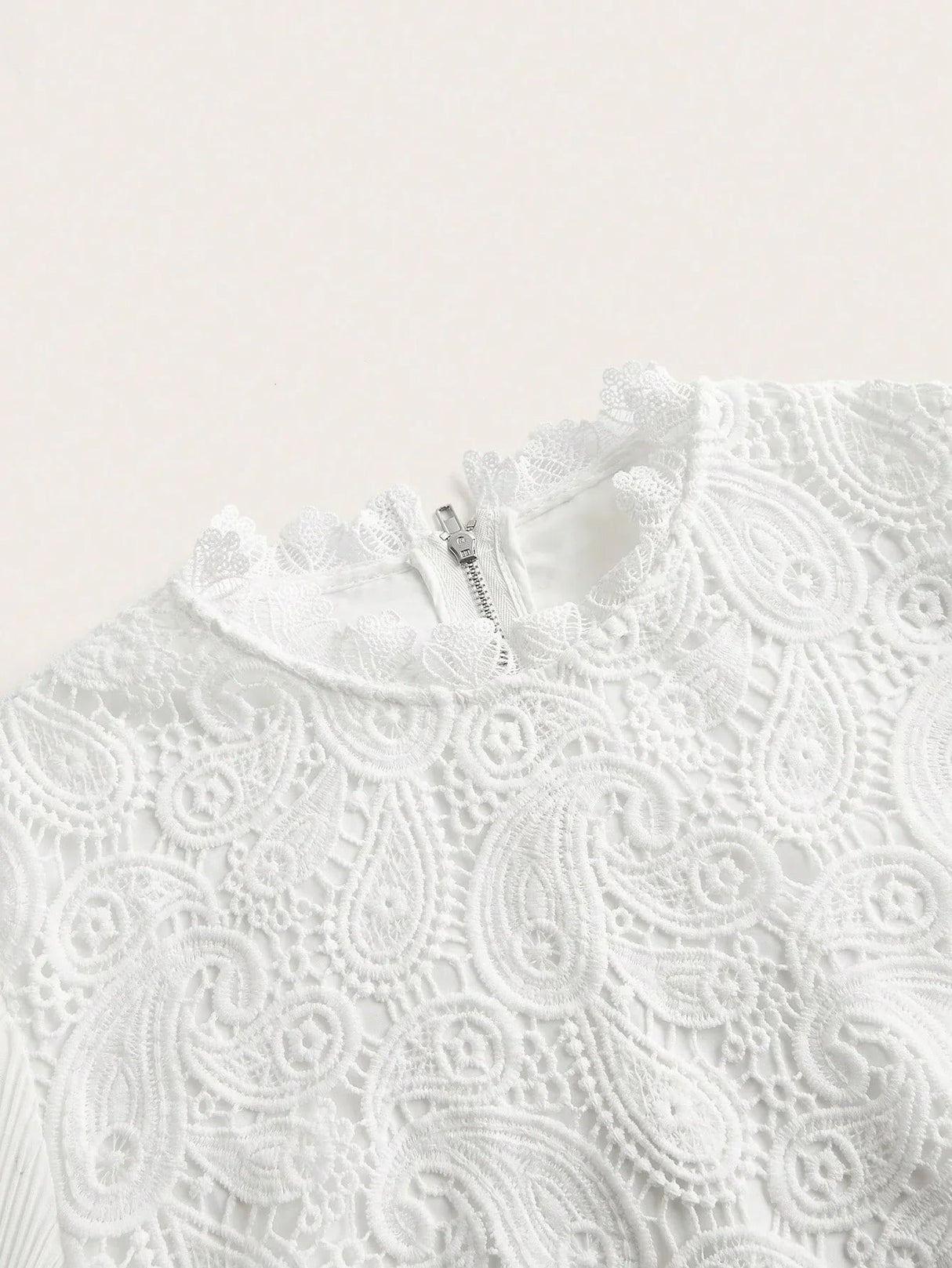 This elegant white dress features intricate lace detailing, showcasing a beautiful paisley pattern that adds a touch of.