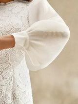 This elegant white dress features intricate lace detailing and soft pleated puff sleeves that create a romantic silhouette..