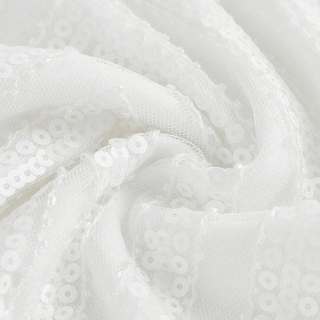 This elegant white dress showcases a shimmering sequined fabric that catches the light beautifully, creating a stunning.