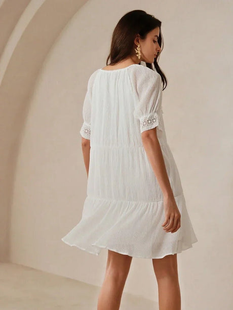 This charming white dress features a relaxed fit with delicate textured fabric and elegant puff sleeves, perfect for a.
