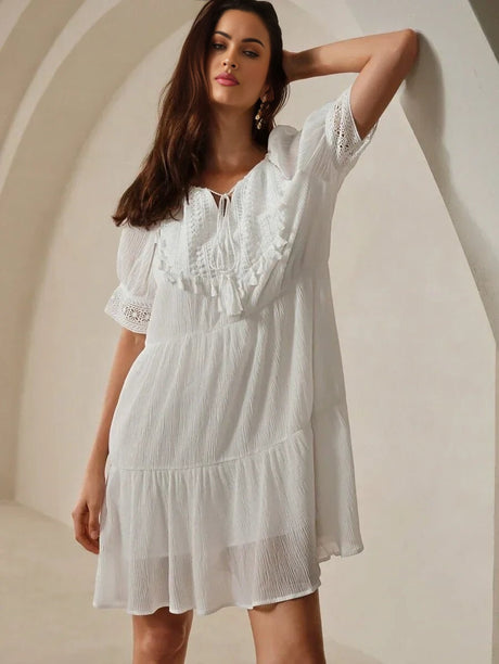 This charming white dress features a flowy silhouette with delicate ruffled detailing and a relaxed fit, perfect for warm.